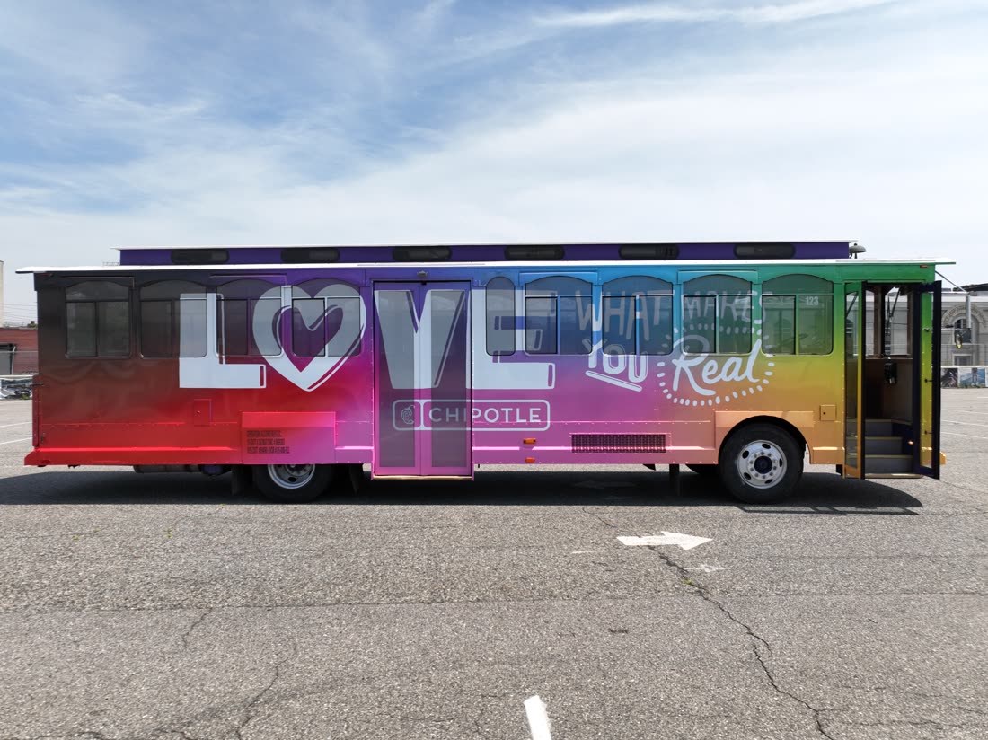 Custom-wrapped trolley bus in a rainbow gradient